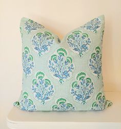 a blue and green pillow sitting on top of a white shelf