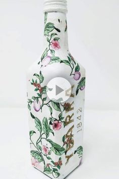 a white vase with flowers and leaves painted on the side, sitting against a white background