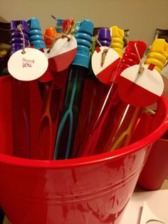 a red bucket filled with lots of colorful toothbrushes and paper hearts attached to them