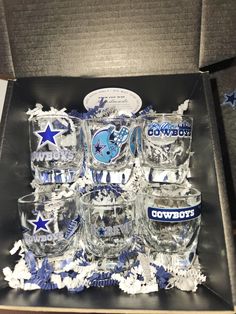 a box filled with lots of glasses on top of a wooden table covered in blue and white confetti