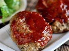 two meat patties covered in ketchup on a plate next to a salad