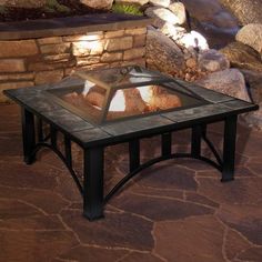 a fire pit sitting on top of a stone floor next to a rock garden wall