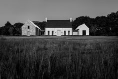 a black and white photo of a house in the middle of a field with tall grass