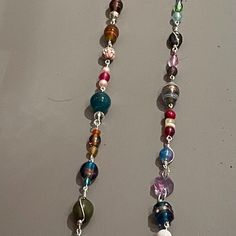 two necklaces with different colored beads hanging from it's sides on a table