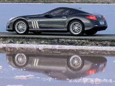 a black sports car parked on the side of a road next to a body of water