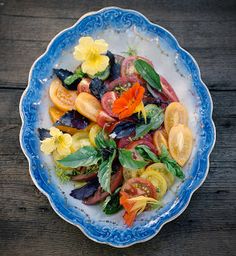 a blue and white bowl filled with lots of different types of food on top of a wooden table