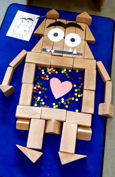 a robot made out of wooden blocks and colored sprinkles on a blue mat