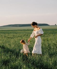 a mother and daughter holding hands in a field