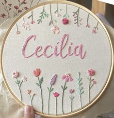 someone is holding up a hand embroidered name and flowers