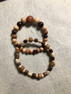 two bracelets made out of wood beads on top of a white cloth covered floor