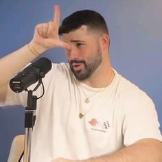 a man with a goatee is making the peace sign in front of a microphone