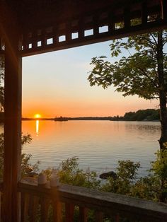 the sun is setting over a lake with trees