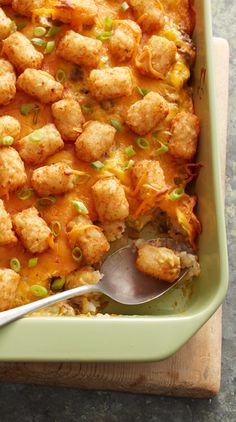 a casserole dish with tater tots and green onions in it, ready to be eaten