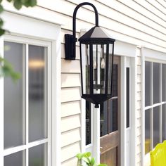 a black lantern hanging from the side of a house next to a yellow lawn chair