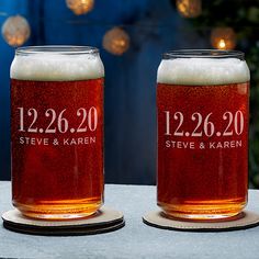 two personalized beer mugs sitting on a table with christmas lights in the background