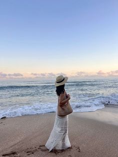 a woman standing on top of a sandy beach next to the ocean