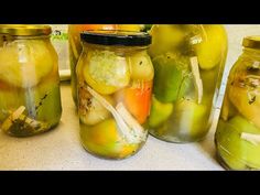 four jars filled with pickles and onions on a counter top next to each other