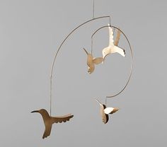 three birds are flying in the air near a circular wind chime that is hanging from it's side