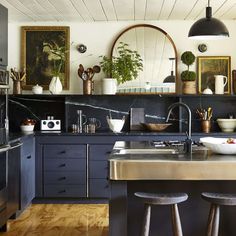 a kitchen with black cabinets and wooden floors, two stools in front of the sink