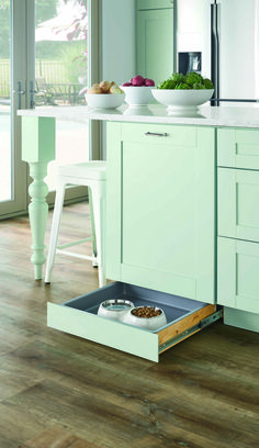 an open drawer in the middle of a kitchen with plates and bowls on top of it