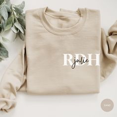 a white sweatshirt with the word ruth on it next to some leaves and a plant