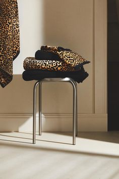 a leopard print blanket sitting on top of a metal chair next to a white wall