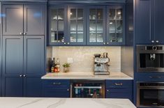 a kitchen with blue cabinets and marble counter tops