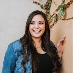 a woman standing next to a wall smiling