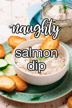 a bowl of salmon dip on a plate with cucumbers and crackers next to it