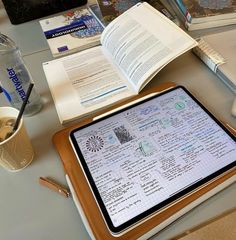 a tablet sitting on top of a table next to a cup of coffee and an open book