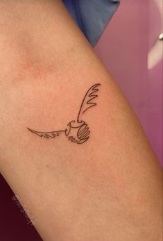 a small bird tattoo on the back of a woman's leg, with an arrow in it