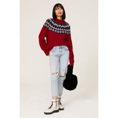 a woman wearing ripped jeans and a red sweater stands in front of a white background