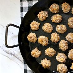 a pan filled with meatballs sitting on top of a table next to a black and white checkered cloth