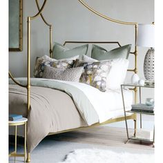 a white bed with gold frame and pillows