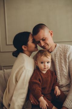 a man and woman sitting next to a baby on a couch