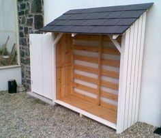 a dog house built into the side of a building with a black roof and door