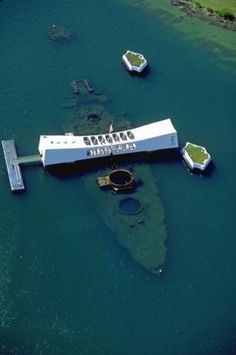 an aerial view of a large boat dock in the middle of water with several smaller boats floating around it