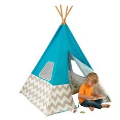 a little boy sitting in front of a teepee