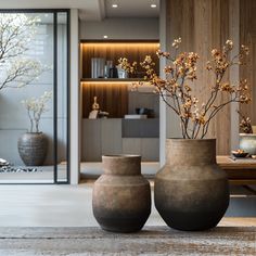 two vases sitting on top of a wooden table next to each other with flowers in them