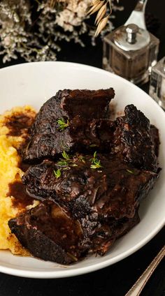 a white plate topped with meat and mashed potatoes