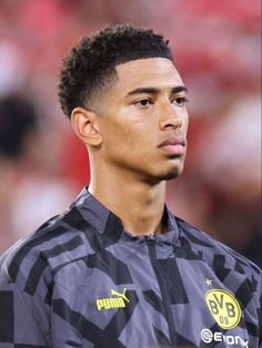 a close up of a soccer player wearing a black and gray jacket with yellow lettering on it