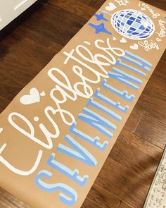 a wooden sign that says welcome to the world with blue and white lettering on it