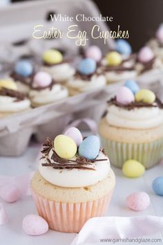 some cupcakes with white chocolate and colored eggs on top are sitting next to each other