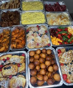 many trays filled with different types of pastries and fruit on top of each other