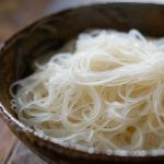 a wooden bowl filled with noodles on top of a table