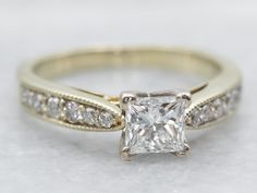 an engagement ring with a princess cut diamond in the center and side stones on each band