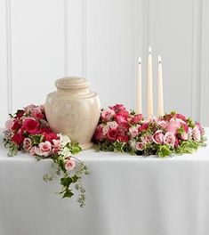 a vase with flowers and candles on a table