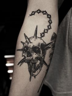 a man's arm with a skull and barbed wire tattoo on the left forearm