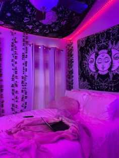 a bed with pink sheets and pillows in a room that has purple lights on the ceiling