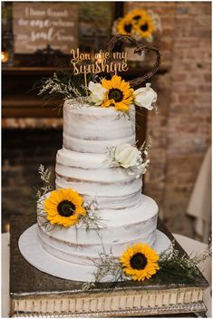 a white wedding cake with sunflowers on top